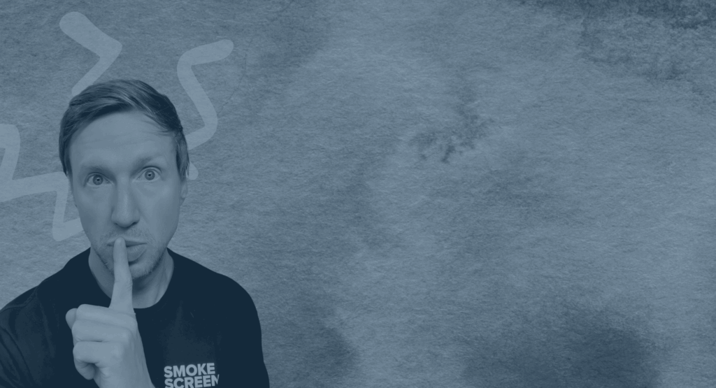 man places finger on lips to suggest silence in smokey blue fog